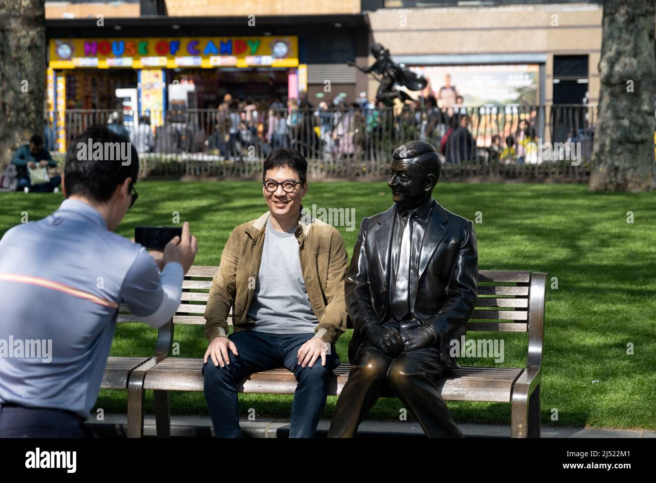 A tourist posing with Mr Bean statue in Leicester Square, London. Stock Photo