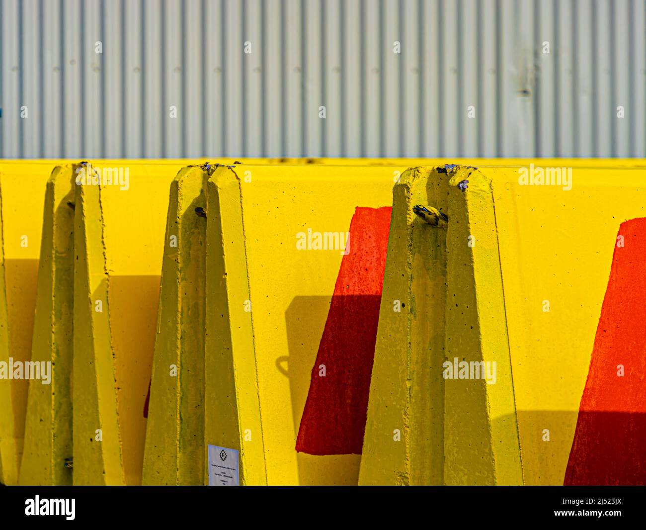A row of yellow and red concrete traffic barriers. Stock Photo