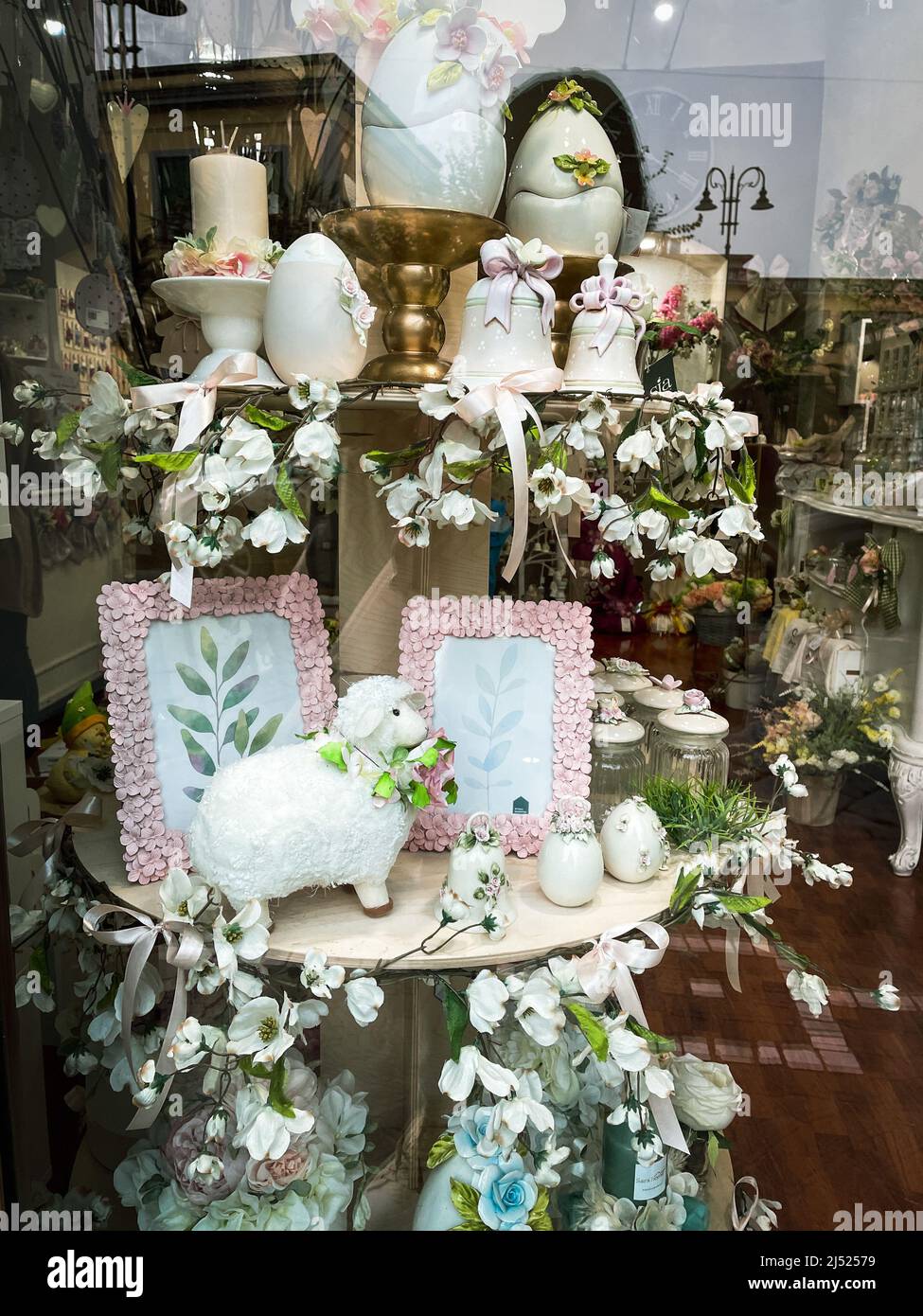 Artistic Easter arrangement, decor and souvenirs on glass showcase with white ceramic eggs, bells and flowers. Stock Photo