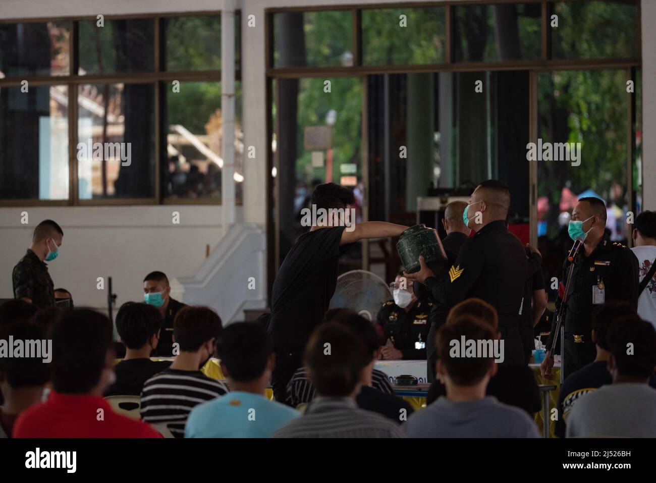 Pathum Thani, Thailand. 17th Apr, 2022. A young man decides to measure his  fortune Draw lots for paper inside the container (black paper does not have  to be military, red card is