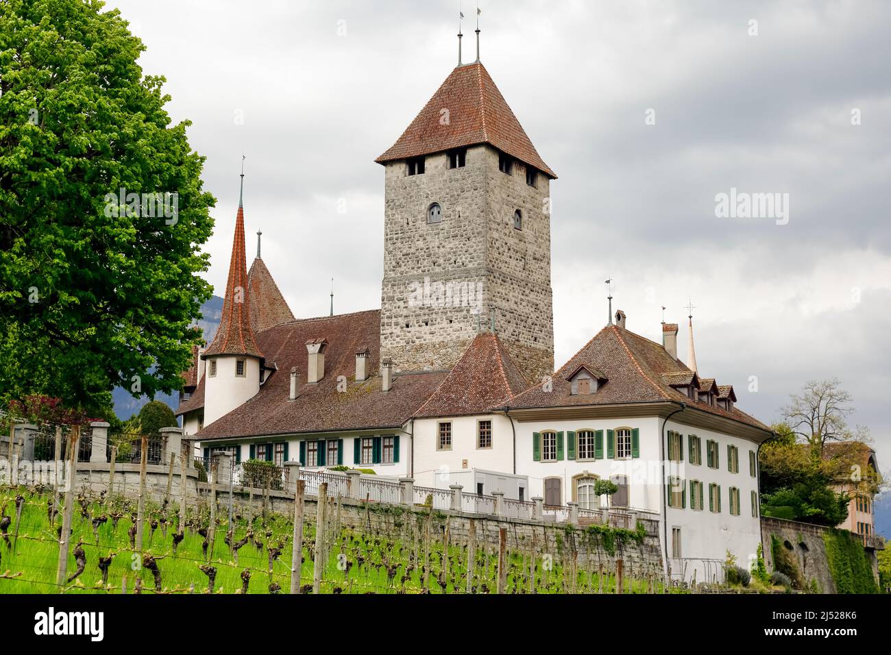 Spiez, Switzerland - 17 April 2017: Spiez Castle can be seen on a hill against a cloudy sky. This Swiss heritage site is in the municipality of Spiez Stock Photo