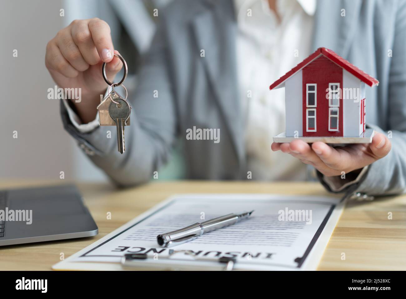 Insurance concept the real estate representative holding a house key on ...