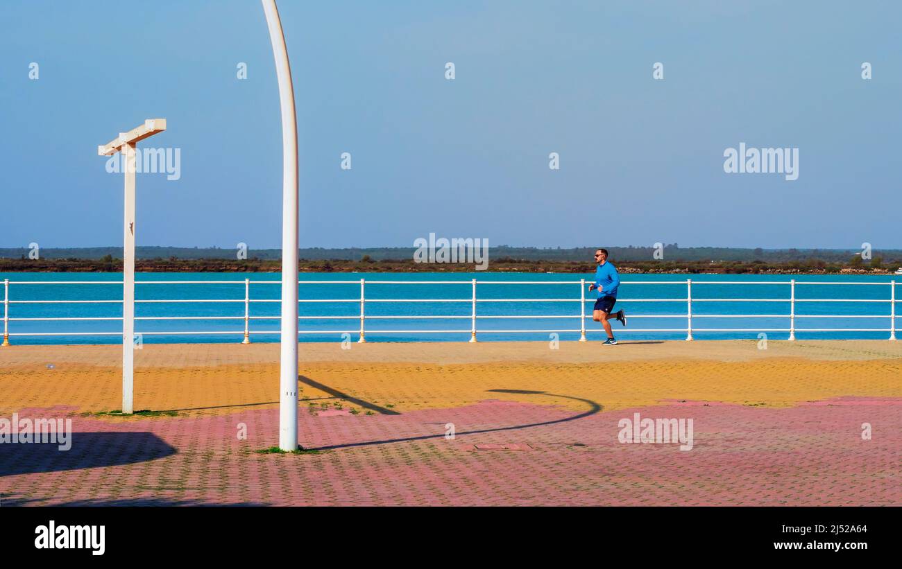 Young man doing sport on the Paseo de la Ría in Huelva on a sunny day. Stock Photo