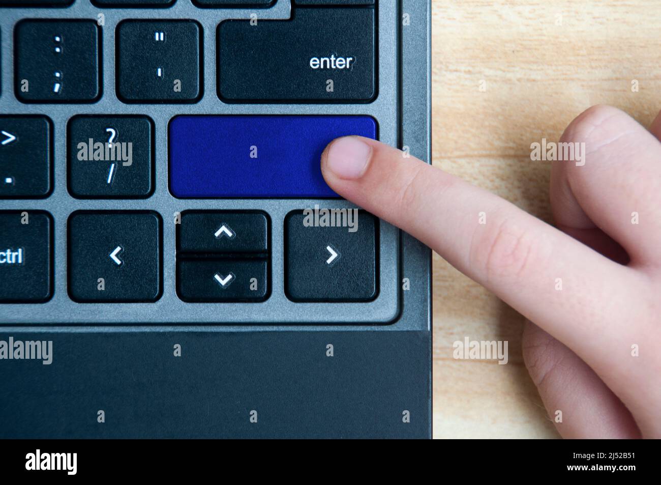 Top view of hand pressing blank blue button on laptop keyboard. Copy space Stock Photo