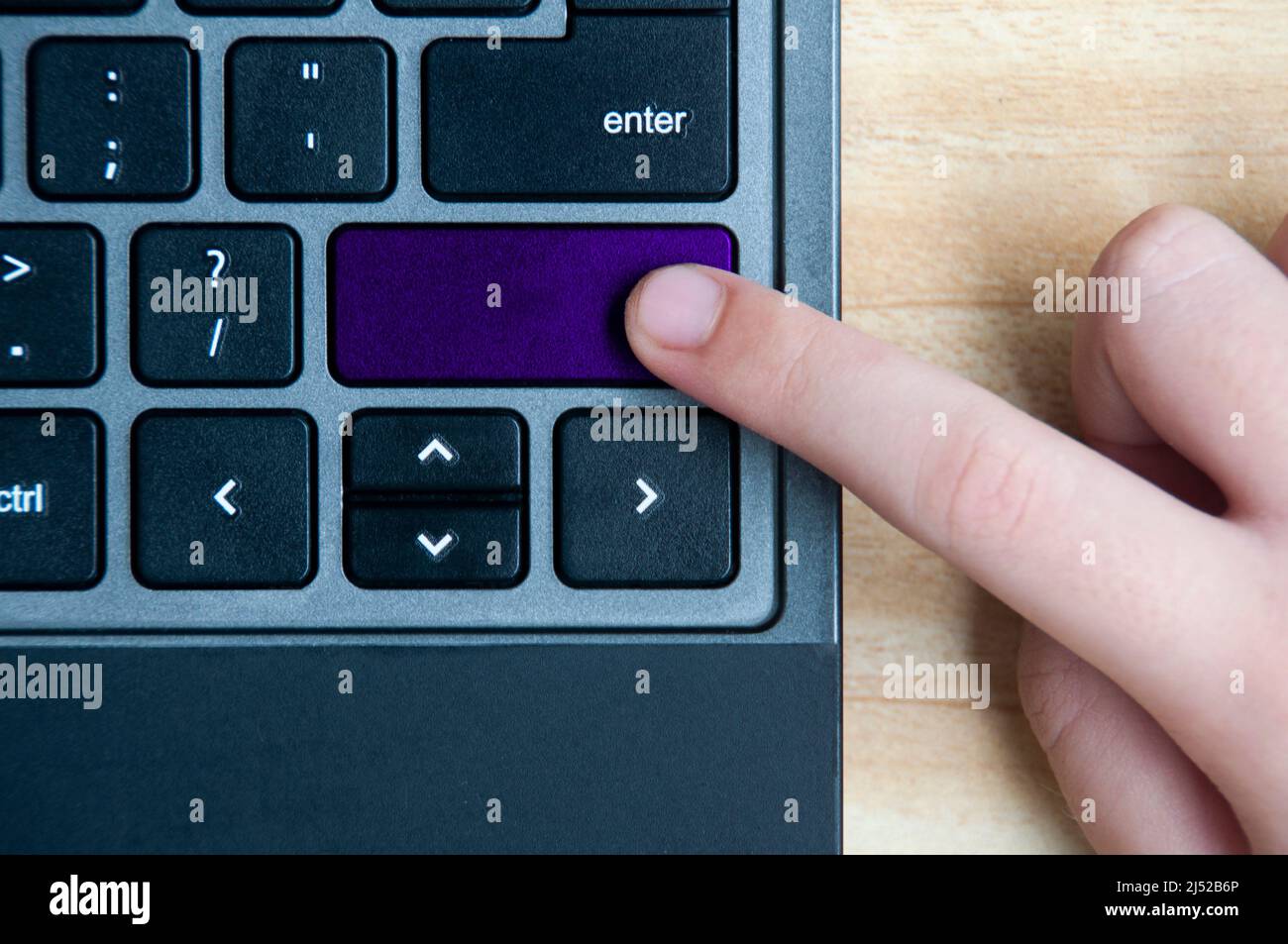 Top view of hand pressing blank purple button on laptop keyboard. Copy space Stock Photo