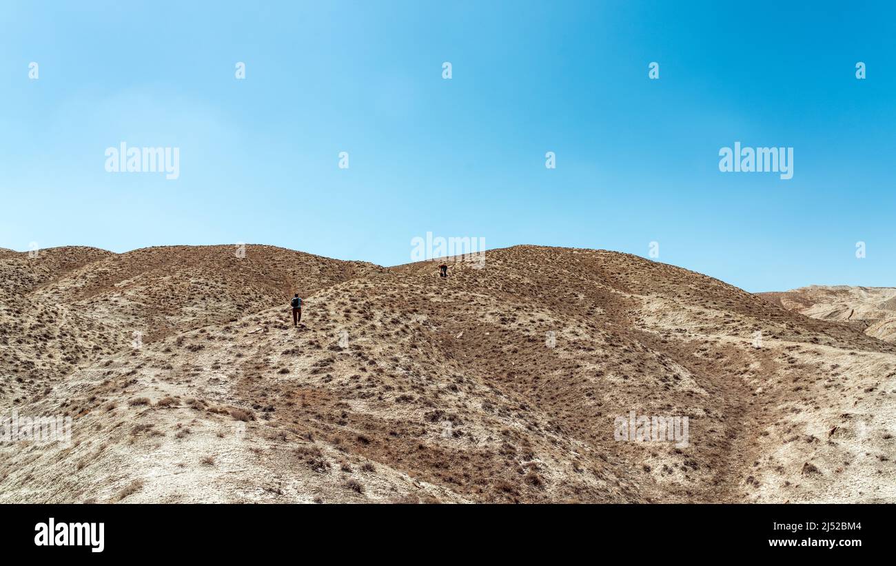 Hikers climb a high hill in a desert area Stock Photo - Alamy