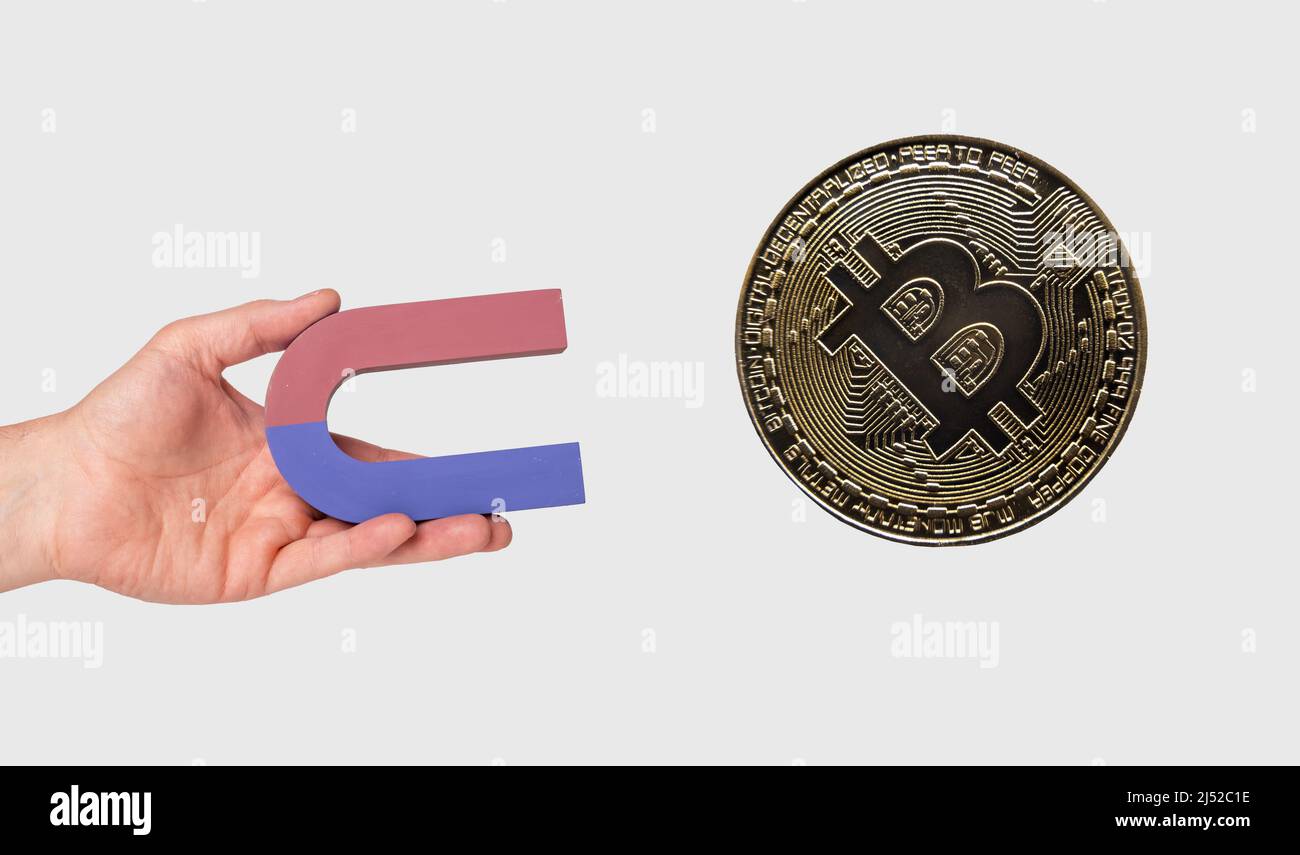 Hand holding magnet and attracting bitcoin. Cryptocurrency, digital money concept. High quality photo Stock Photo