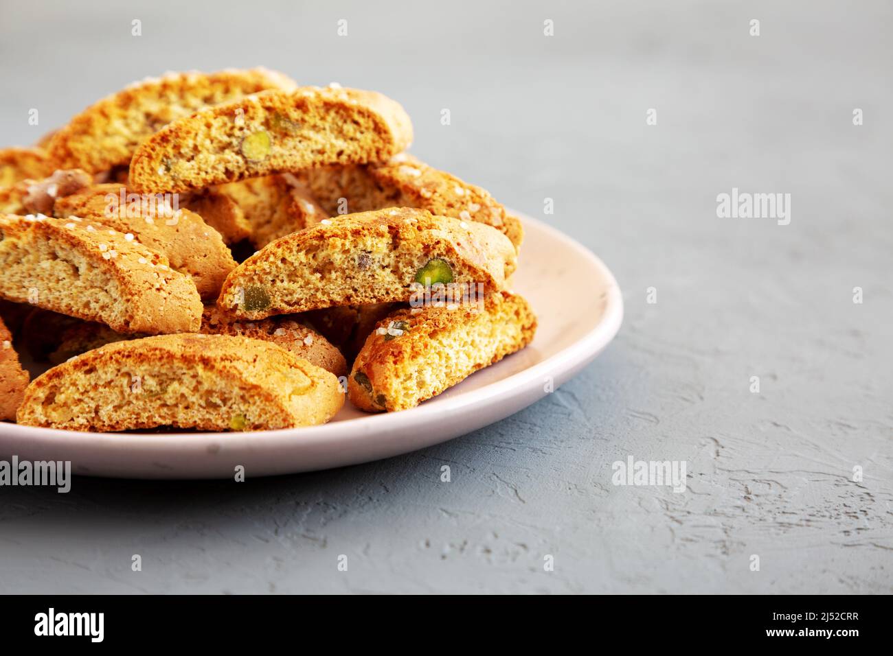 Homemade Italian Cantuccini with Pistachios and Citron on a Plate, side view. Crispy Pistachio and Citron Cookies. Space for text. Stock Photo