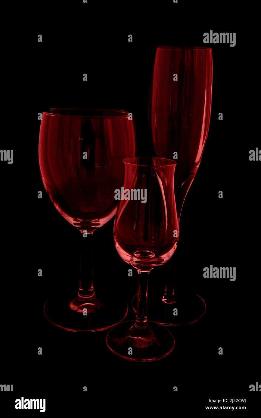 Three wine glasses with black background and red tint. Stock Photo