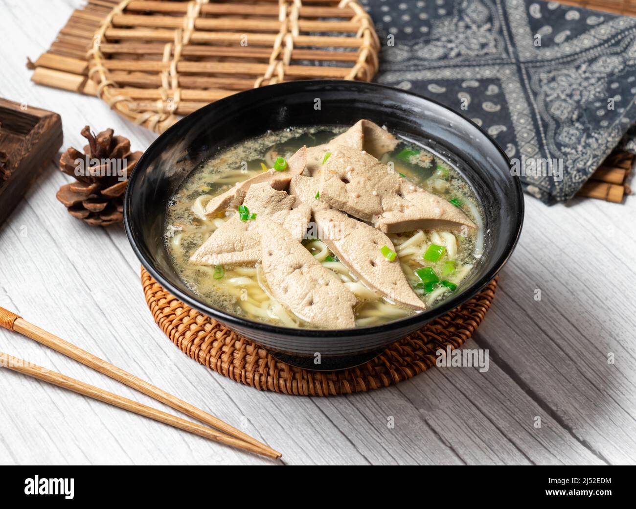 Pork liver noodle soup in a dish isolated on wood table side view