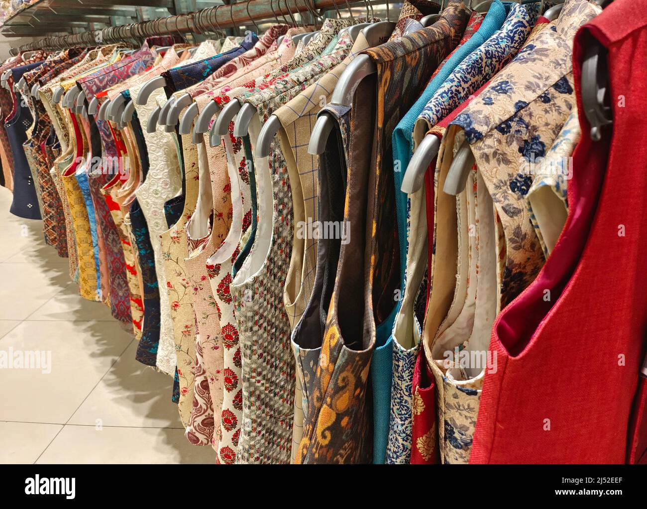 Indian men latest fashion dress hung on hangers, in display in retail shop in market, wedding wear for men India Stock Photo