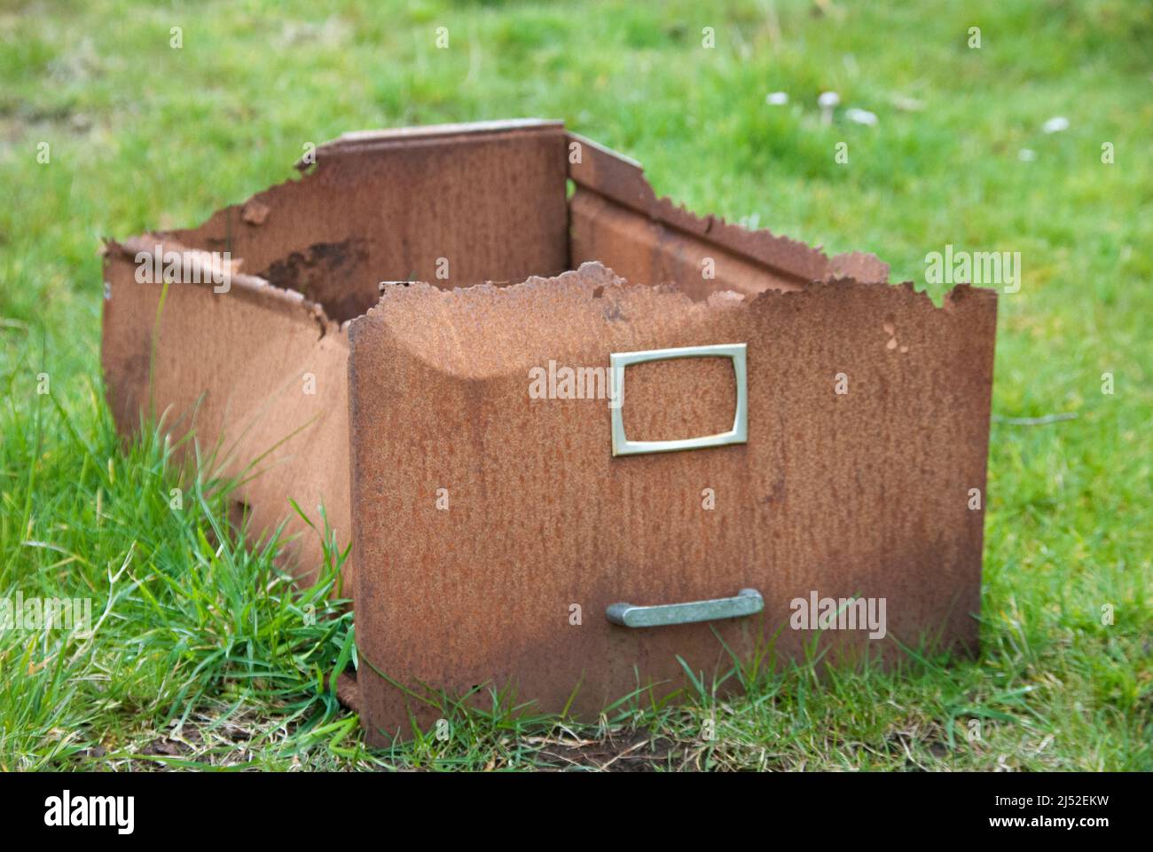 Old, rusty filing cabinet drawer lying on a field. Stock Photo