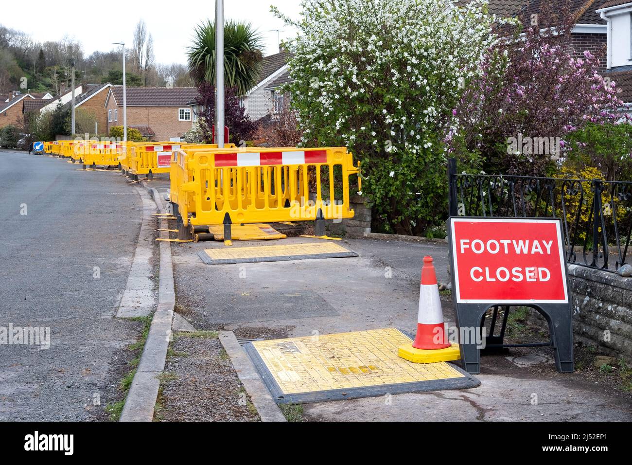 A long row of plastic barriers along a closed footpath pavement as Wales and West Utilities work on upgrading gas supplies to homes with plastic pipes Stock Photo