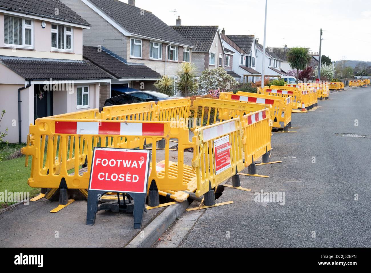 A long row of plastic barriers along a closed footpath pavement as Wales and West Utilities work on upgrading gas supplies to homes with plastic pipes Stock Photo