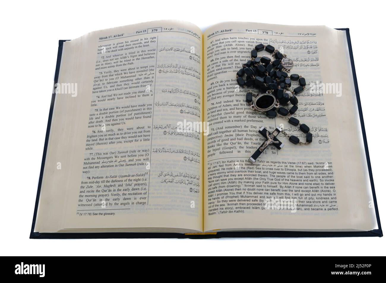 Catholic rosary beads sitting on top of an open Qu'ran. Stock Photo