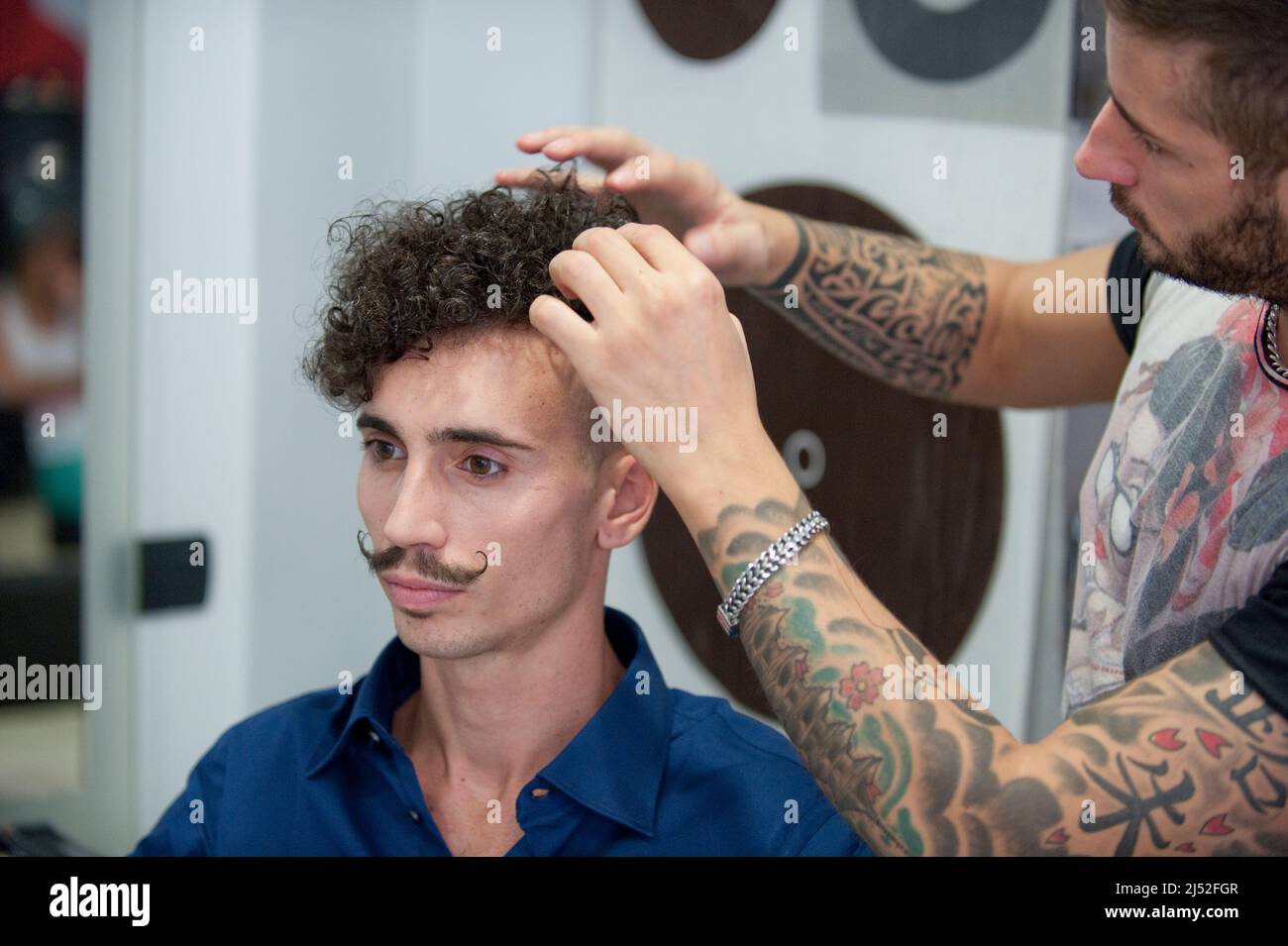 Hairdresser working on a curly man with moustache Stock Photo