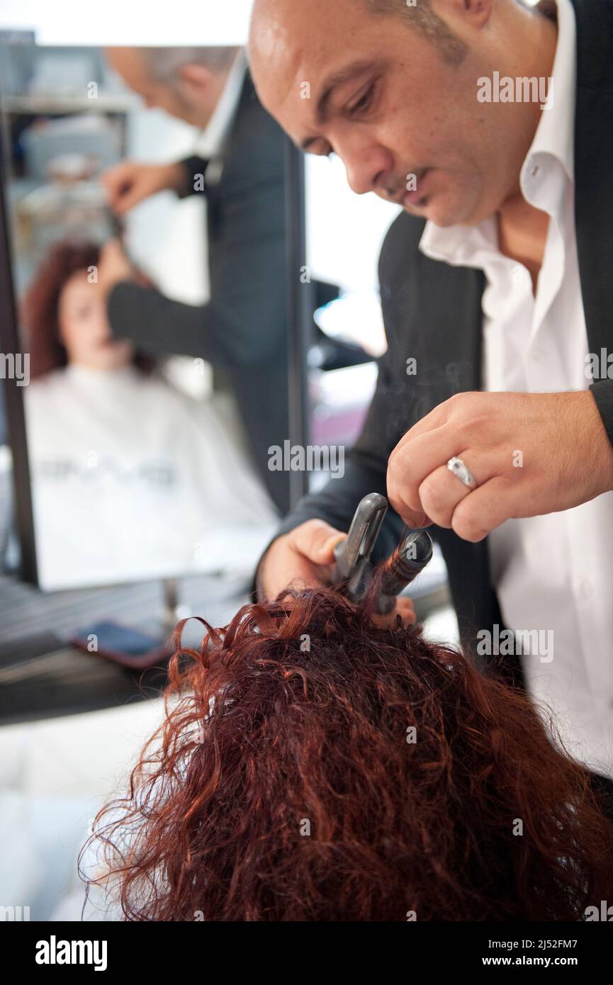 Hairstylist working on a curly red haircut Stock Photo