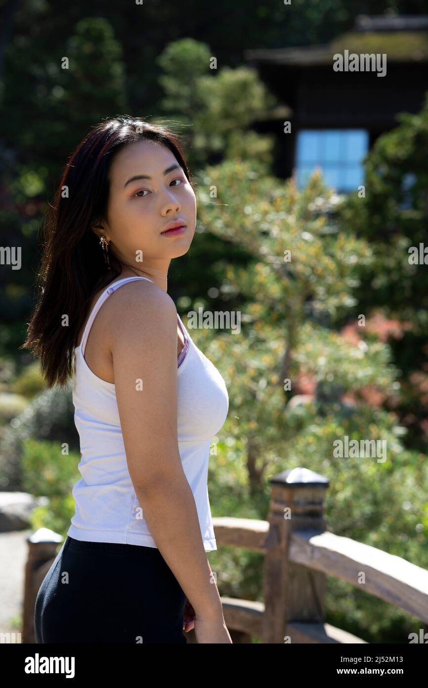 Young Woman in Casual Clothes on a Bridge Over a Japanese Koi Pond Stock Photo