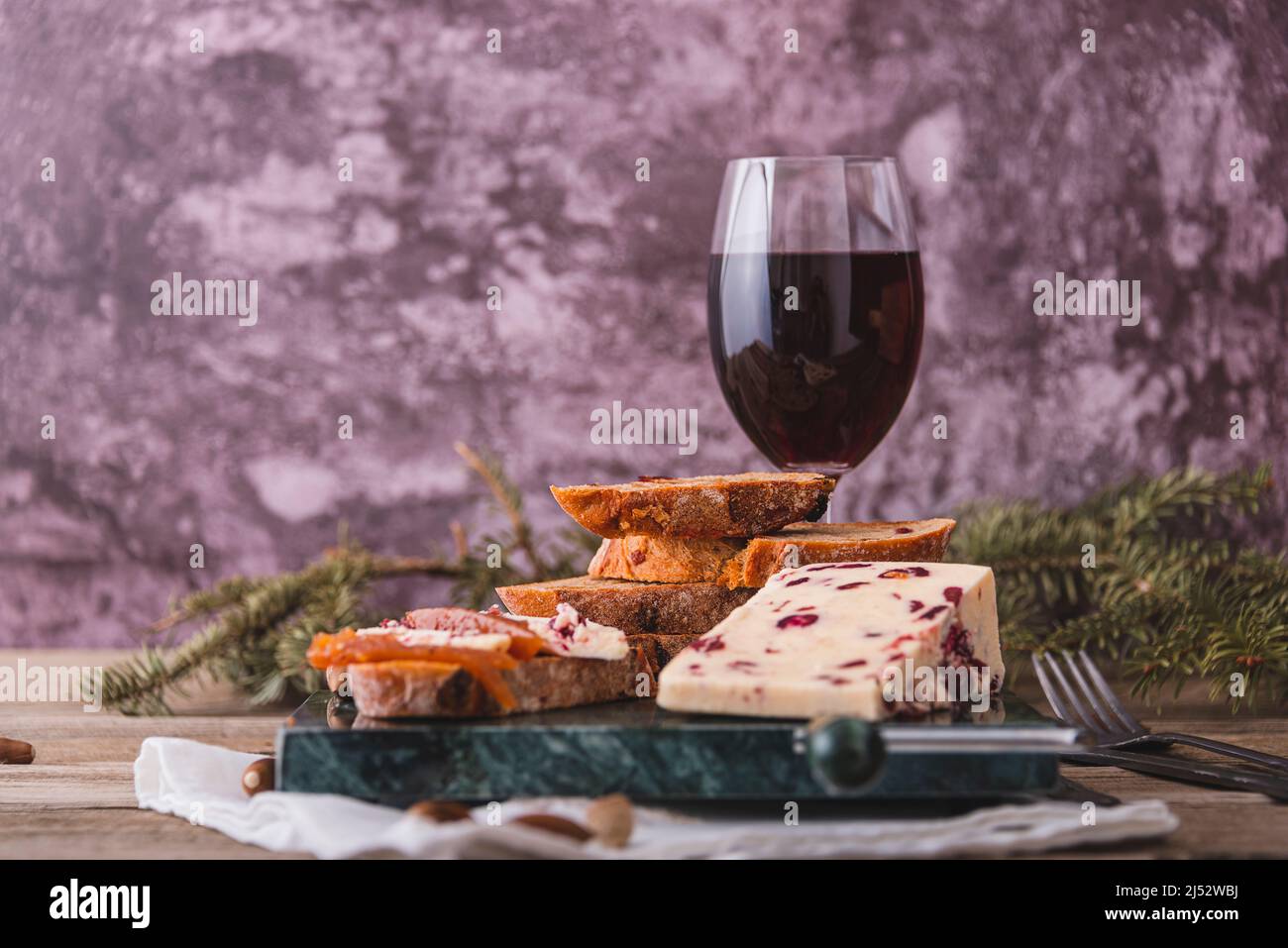 Delicious British Cheddar cheese with cranberry on a marble cheese cutting table. Stock Photo