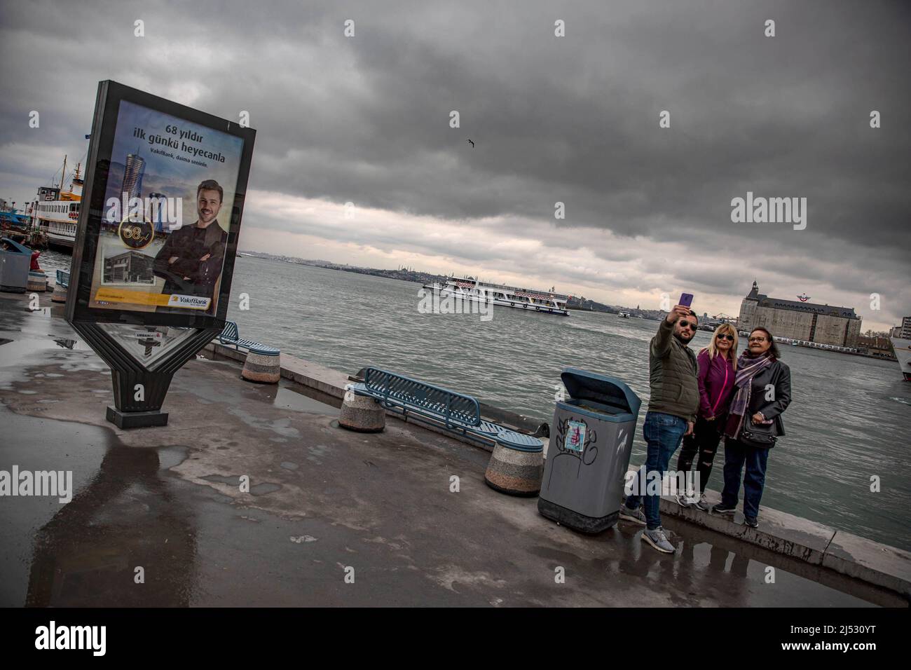 Istanbul, Turkey. 19th Apr, 2022. A group takes selfies on Kadikoy beach with a background of Haydarpasa Train Station. (Credit Image: © Onur Dogman/SOPA Images via ZUMA Press Wire) Stock Photo