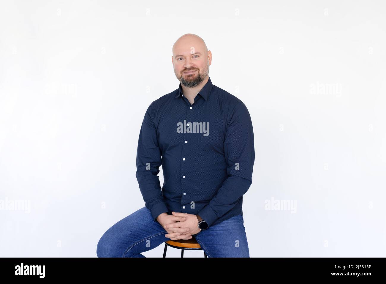 Portrait of pleased middle-aged man wear blue shirt, jeans sitting on ...