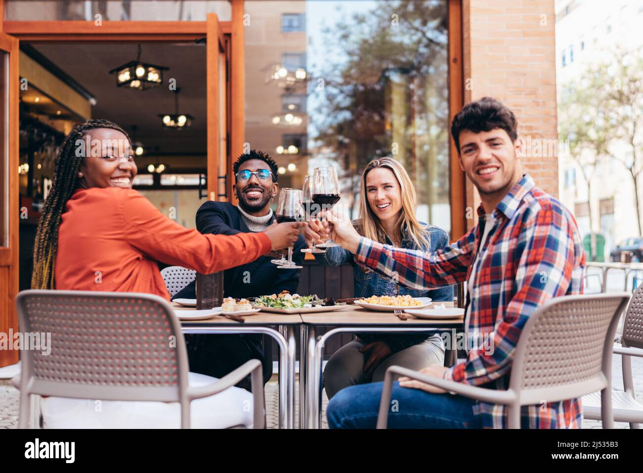 portrait of 4 smiling friends of different ethnicities toasting with red wine Stock Photo