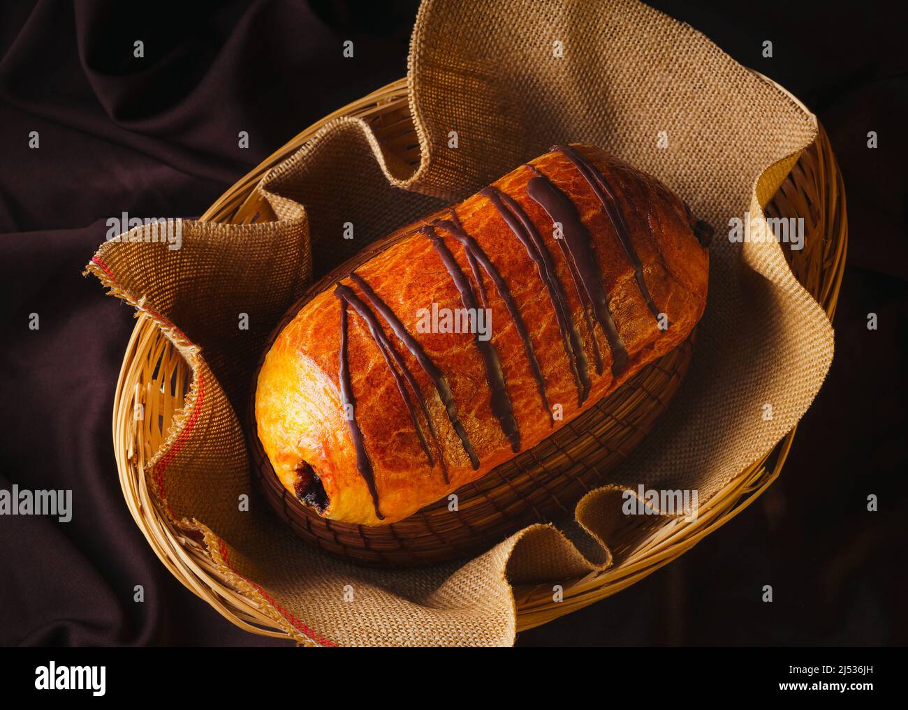 Homemade bread filled with jam with melted chocolate in a wooden basket with rustic black background, gourmet bakery. Traditional Mexican sweet bread. Stock Photo