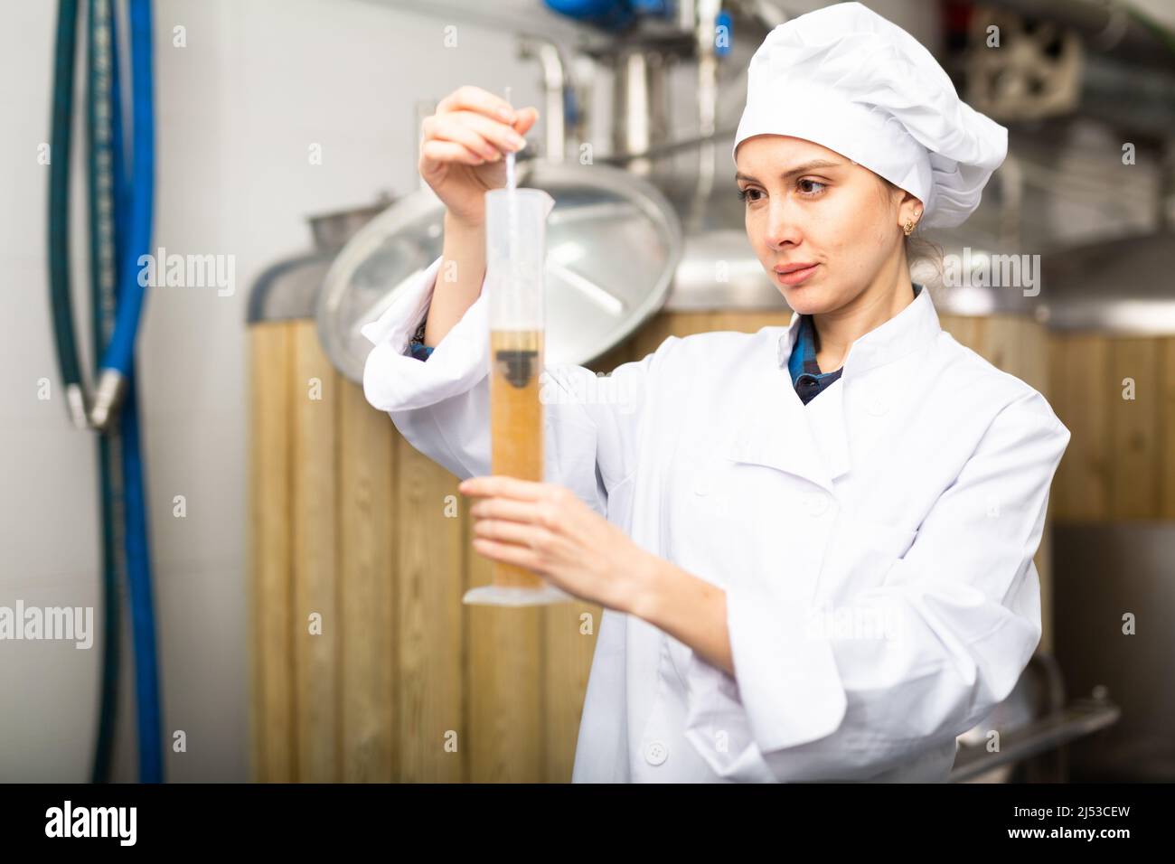Woman brewer measuring alcoholic content in beer with hydrometer Stock