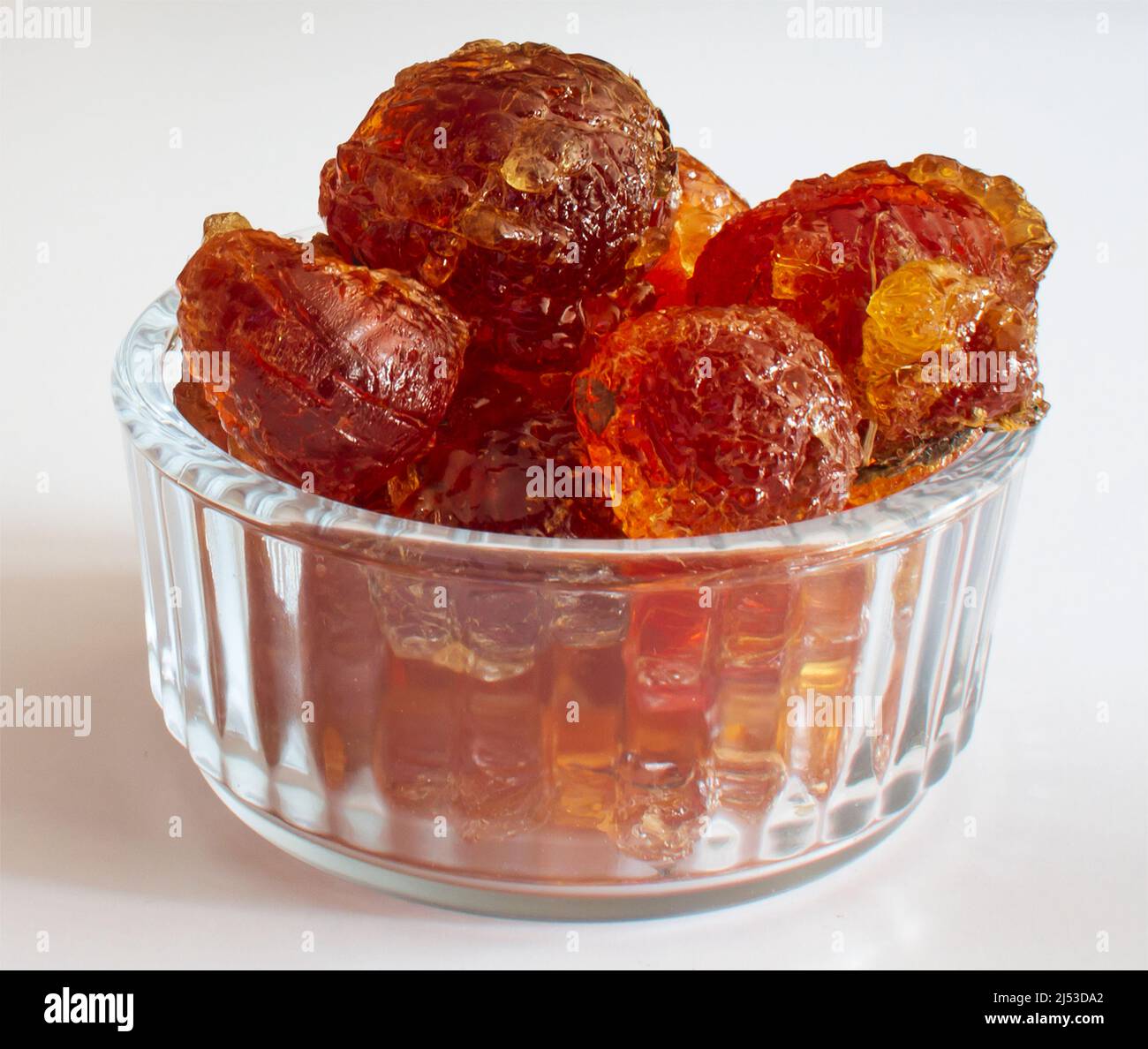 gum arabic chunky pieces in glass bowl closeup on white background Stock Photo