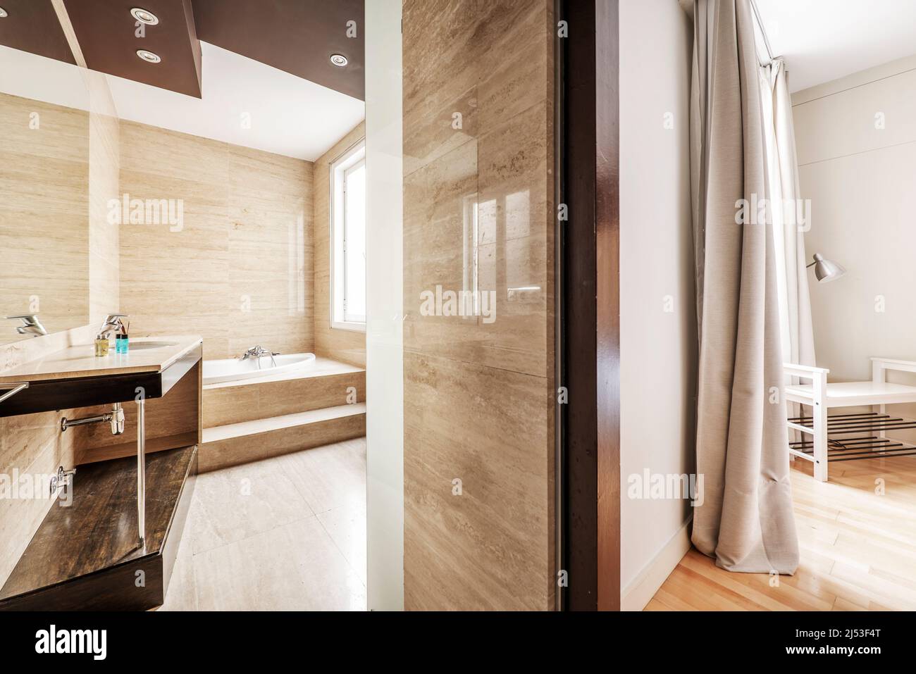 Bathroom with whirlpool tub and polished marble cladding and hardwoods in an en-suite bedroom Stock Photo
