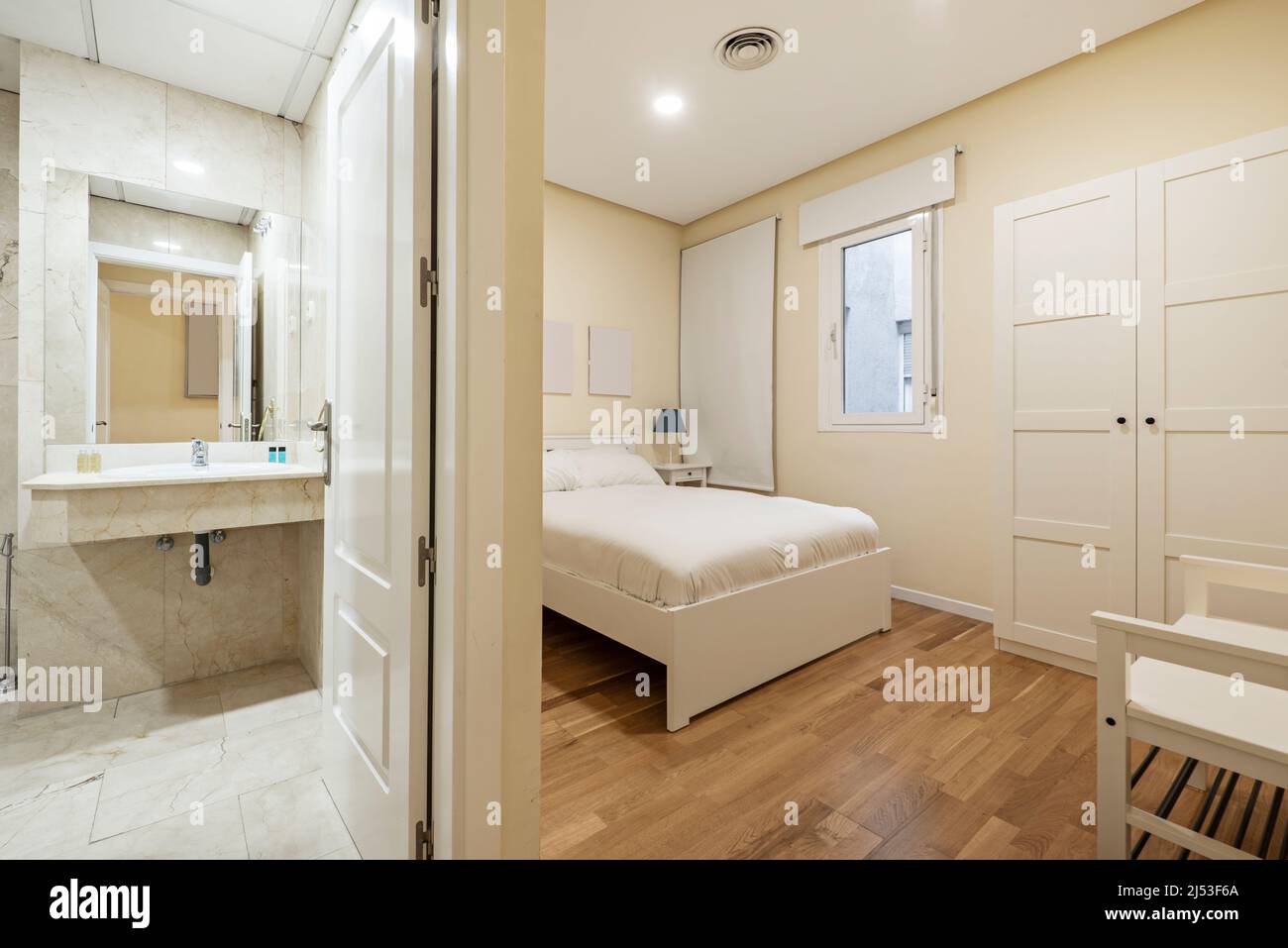en-suite bedroom with bathroom with marble tiles, white wood carpentry and parquet and marble floors Stock Photo