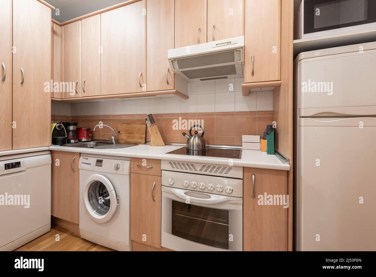 kitchen with light wood furniture with integrated white appliances
