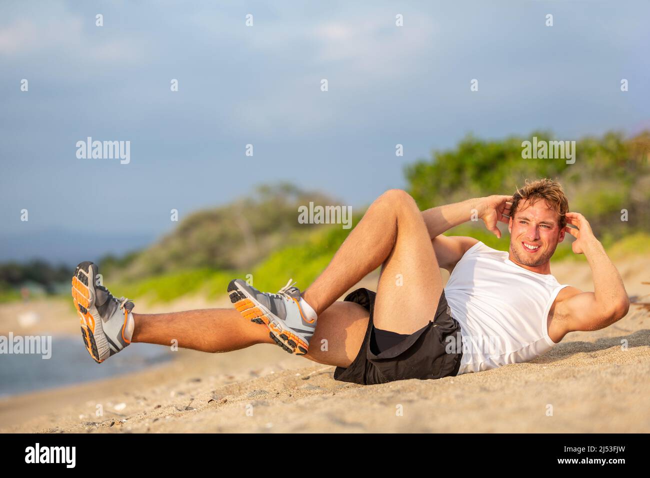 Exercise sit up fitness man doing situps outside in summer beach. Fit athlete working out cross training bicycle crunches to activate obliques mucles Stock Photo