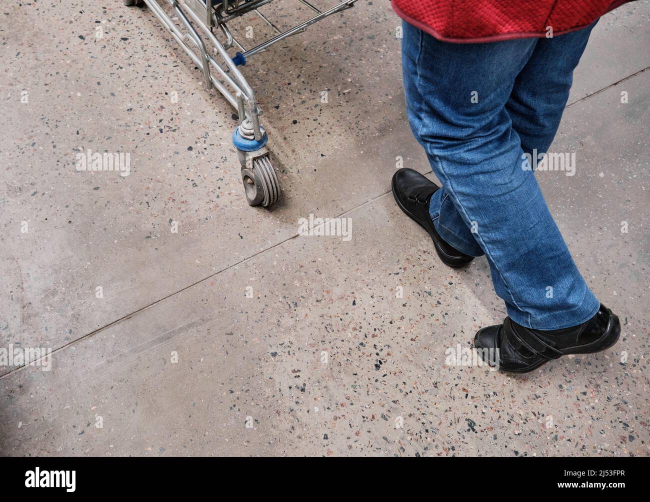 Women feet walk through the mall. A woman carries a grocery cart in front of her Stock Photo