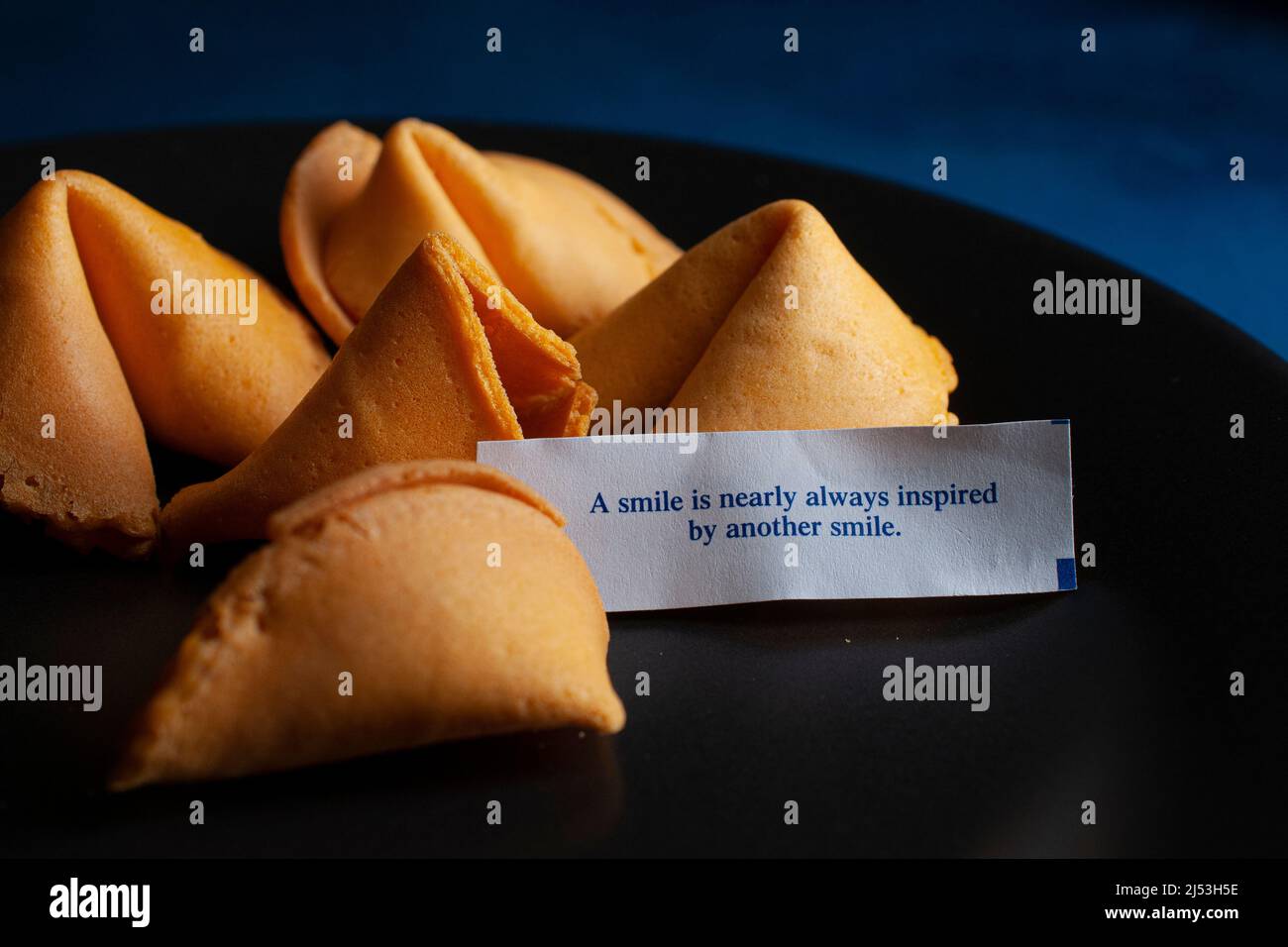 Chinese fortune cookies on a black plate and on a dark blue table Stock