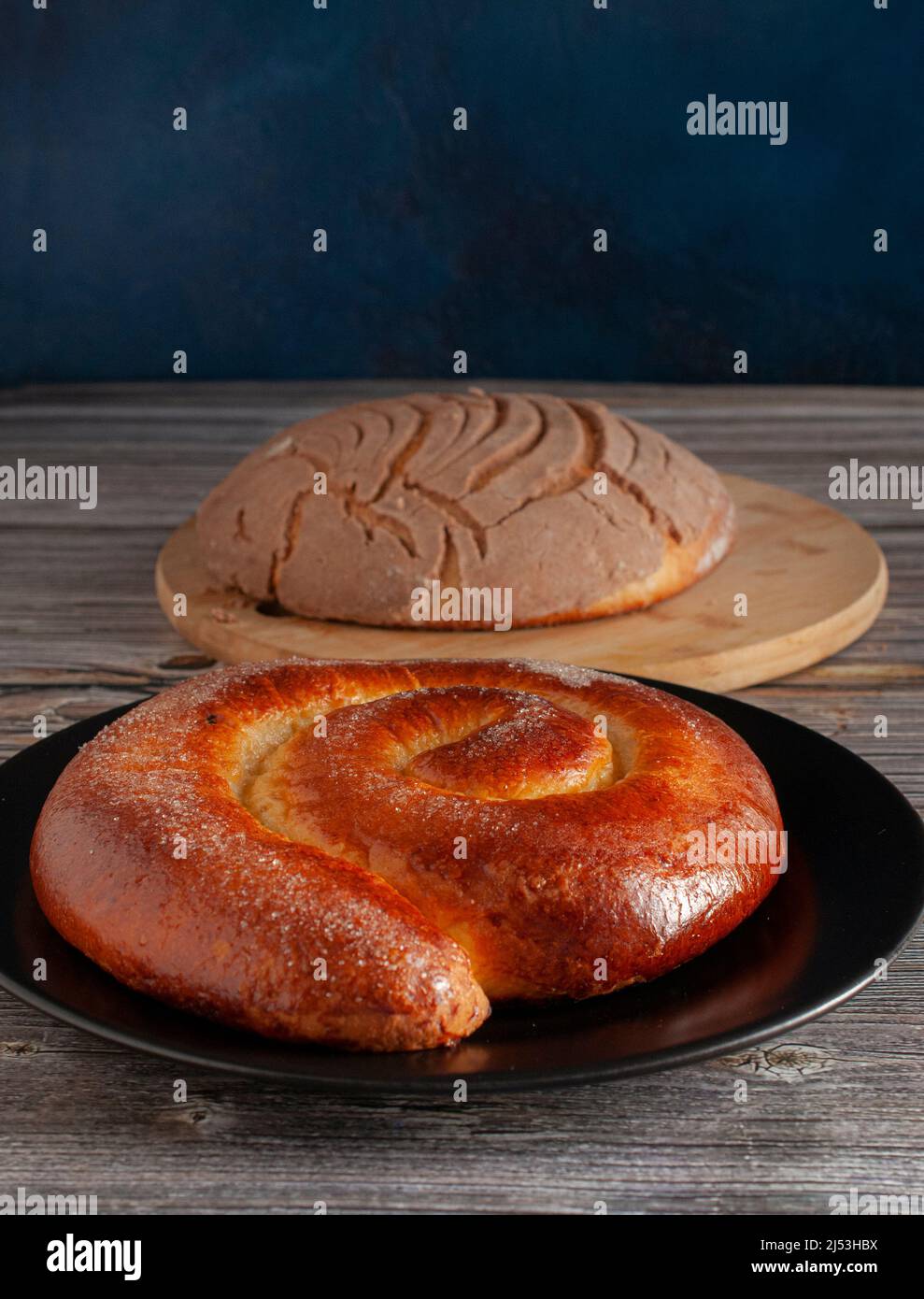 Mexican vanilla sweet bread roll stuffed with creamy cheese and a CONCHA on a wooden cutting board, both from oaxaca. A traditional bakery Stock Photo