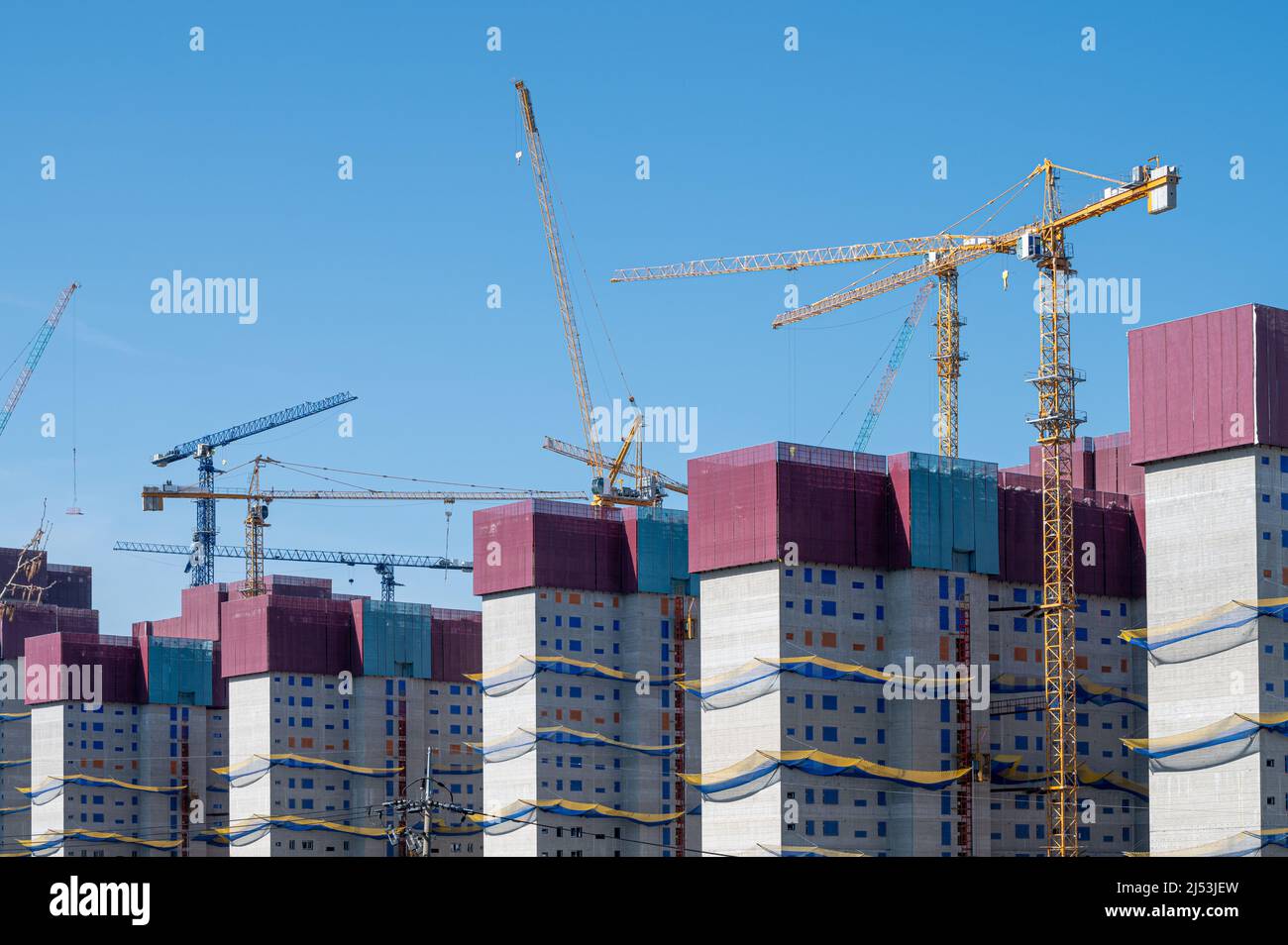 Panorama with many construction tower cranes in clear blue sky. Stock Photo