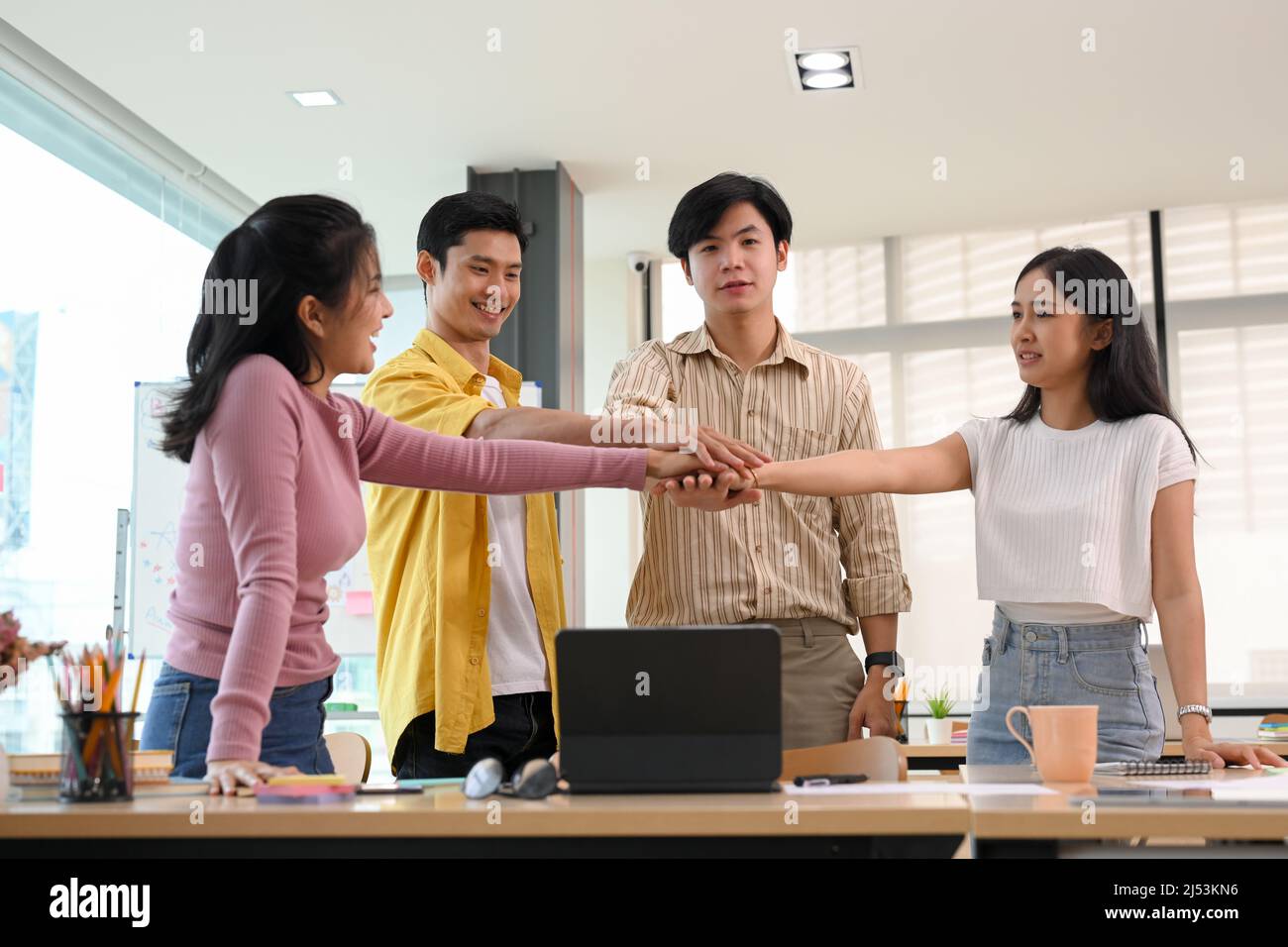 A group of Asian young business startup putting their hands together