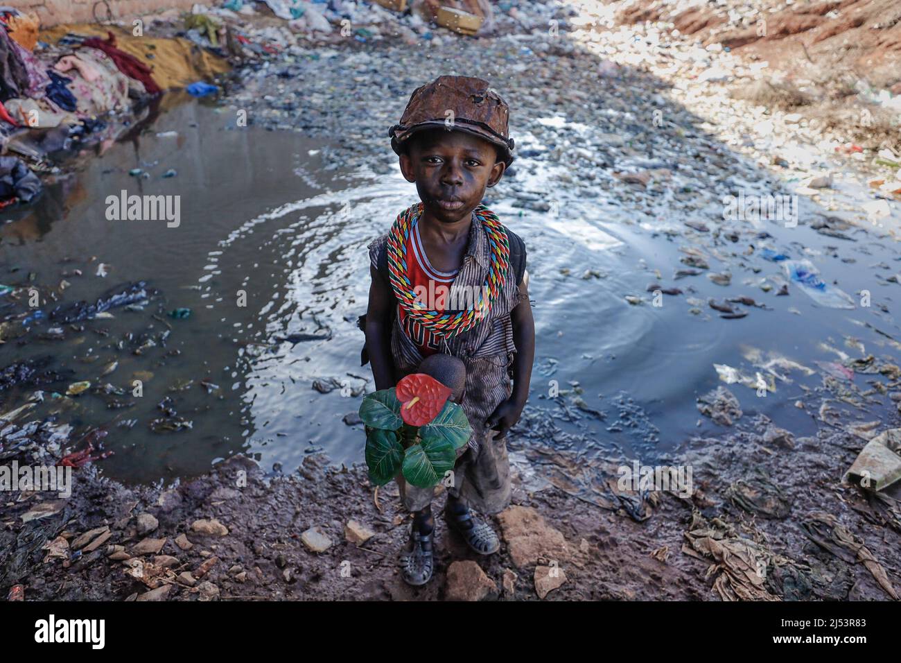 Nairobi, Kenya. 10th Jan, 2022. The young boy actor in his post-apocalyptic  costume poses for a photo by a water waste dump during a film production  for a music video. Artists from