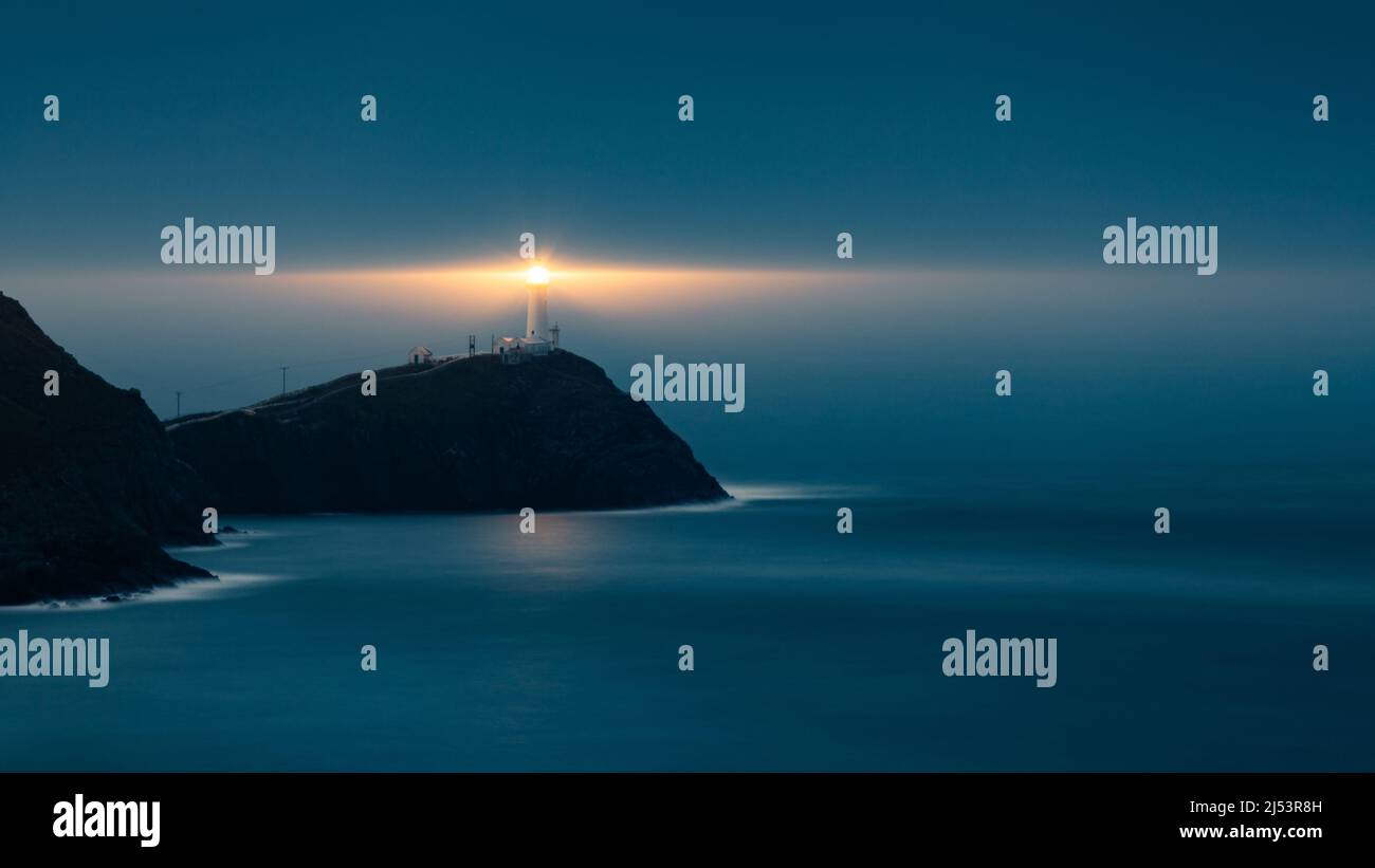 Lighthouse on a stormy night providing a beacon of safety to ships. The ...