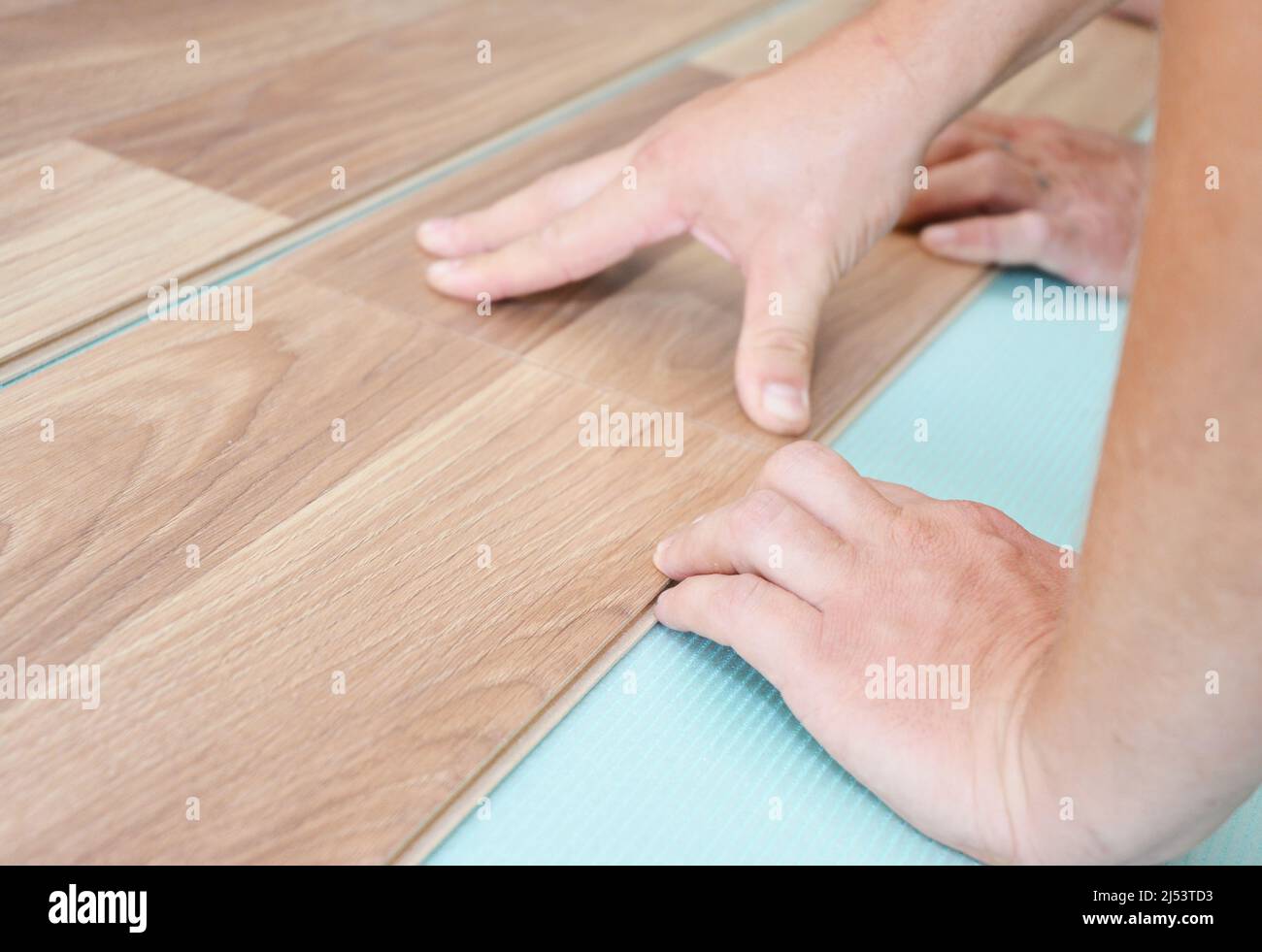 Contractor installing wooden laminate flooring with insulation and