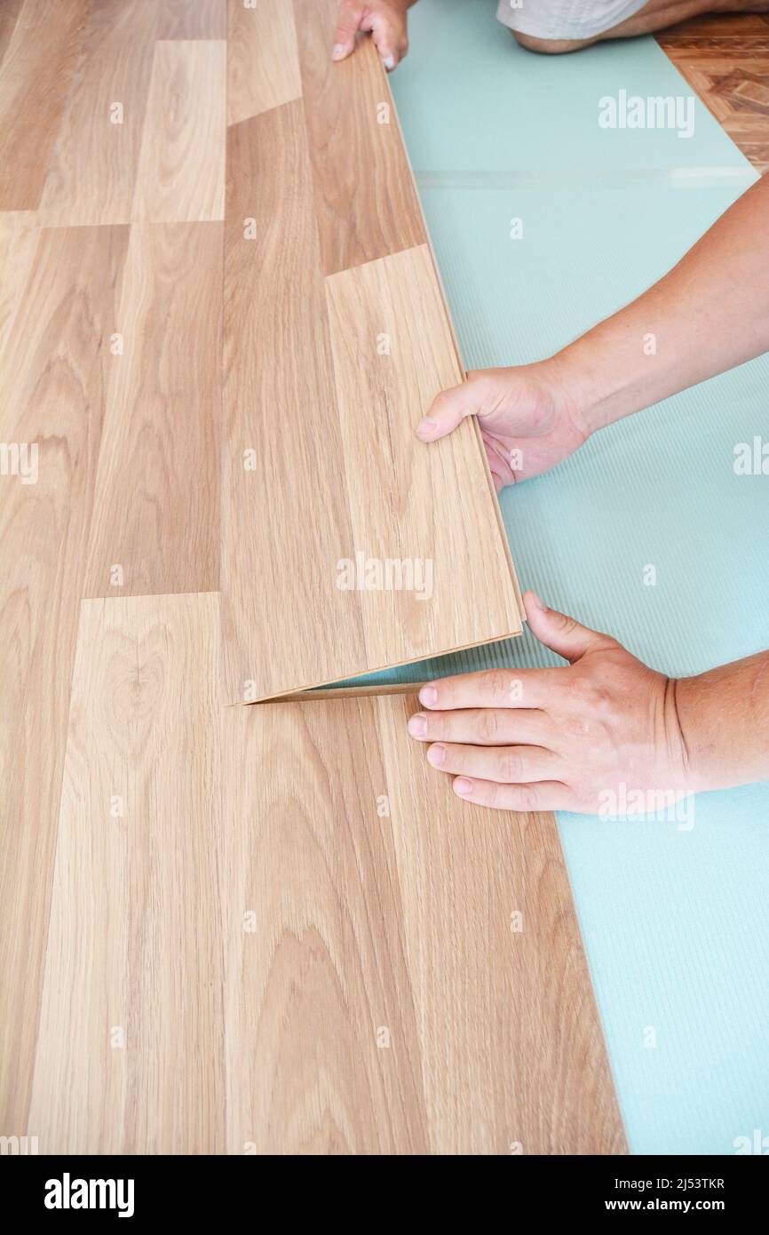 Contractor installing wooden laminate flooring with insulation and