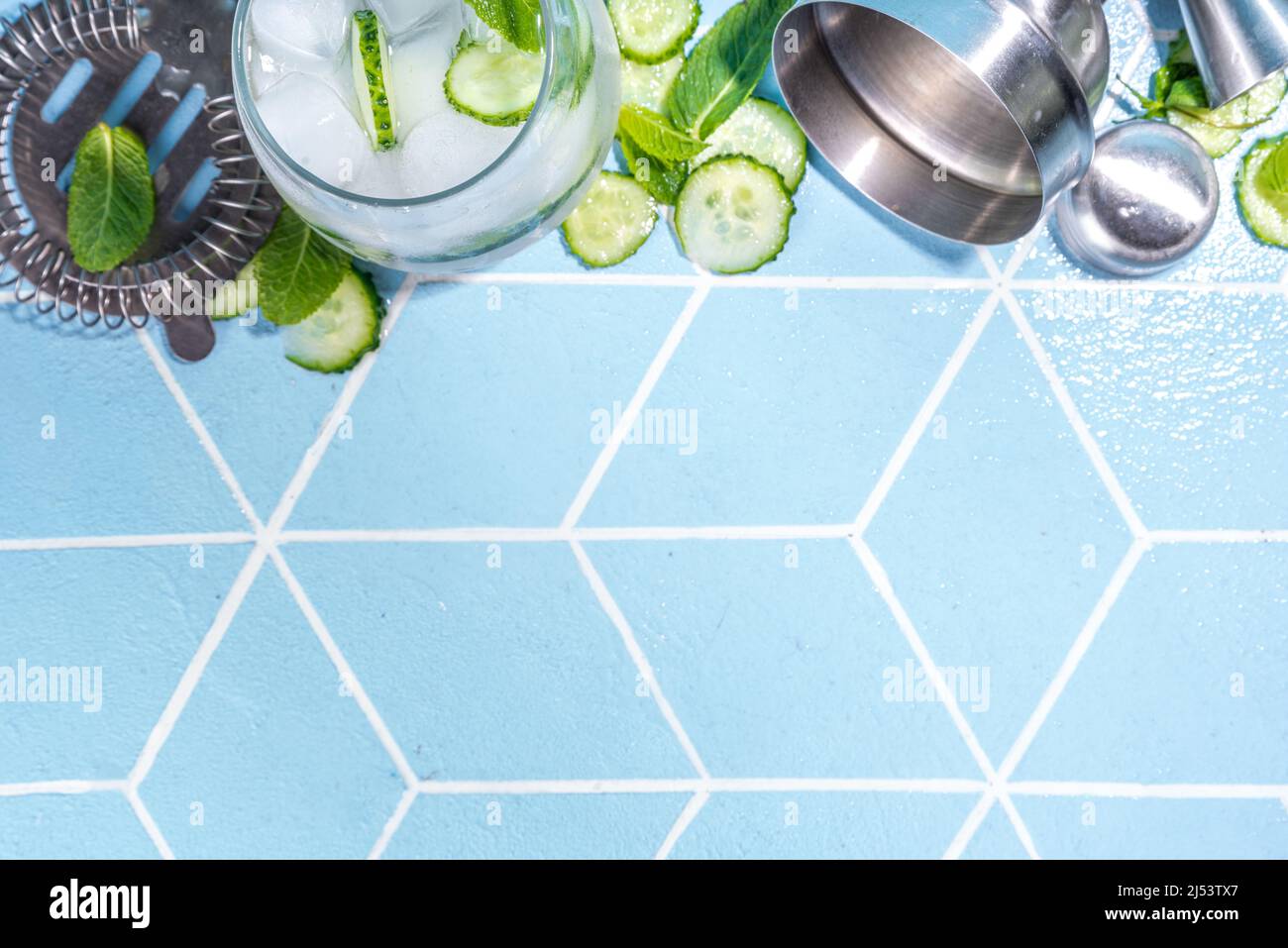 Refreshing summer drink - detox mint, cucumber, lemon cocktail. On light blue tiled table, bright sunlight, copy space. Two glass with cucumber infuse Stock Photo