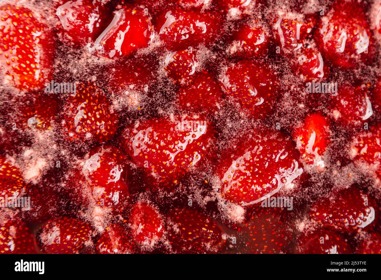 CLOSE UP: Strawberry jam. Homemade Strawberry jam in making progress boiling. Process of making homemade strawberry jam. Red sweet syrup boiling on the stove closeup. Cooking strawberry jam close up. Stock Photo