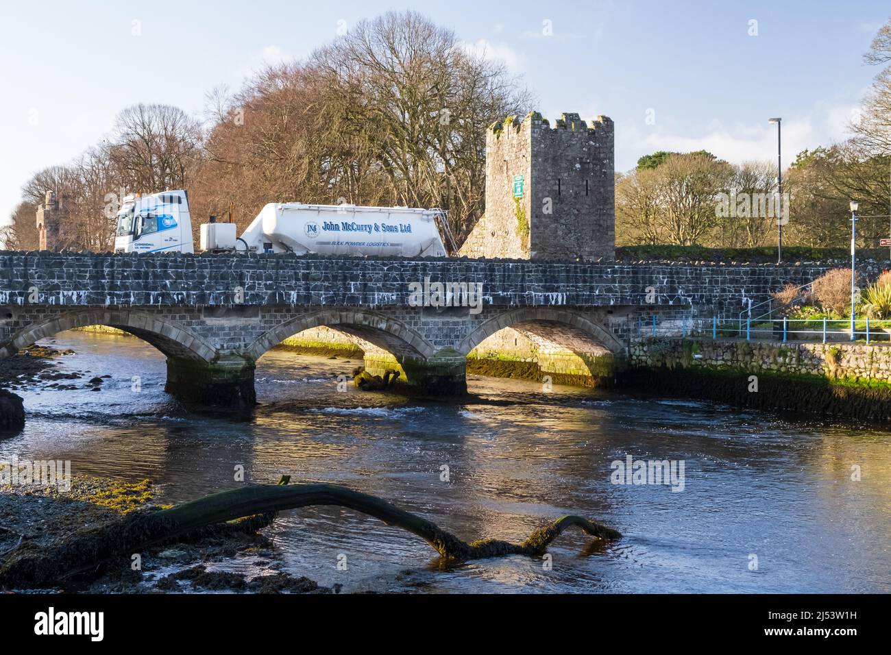 White lorry of John McCurry and Sons Ltd passing over the river at the historic village of Glenarm in County Antrim, Northern Ireland. Stock Photo