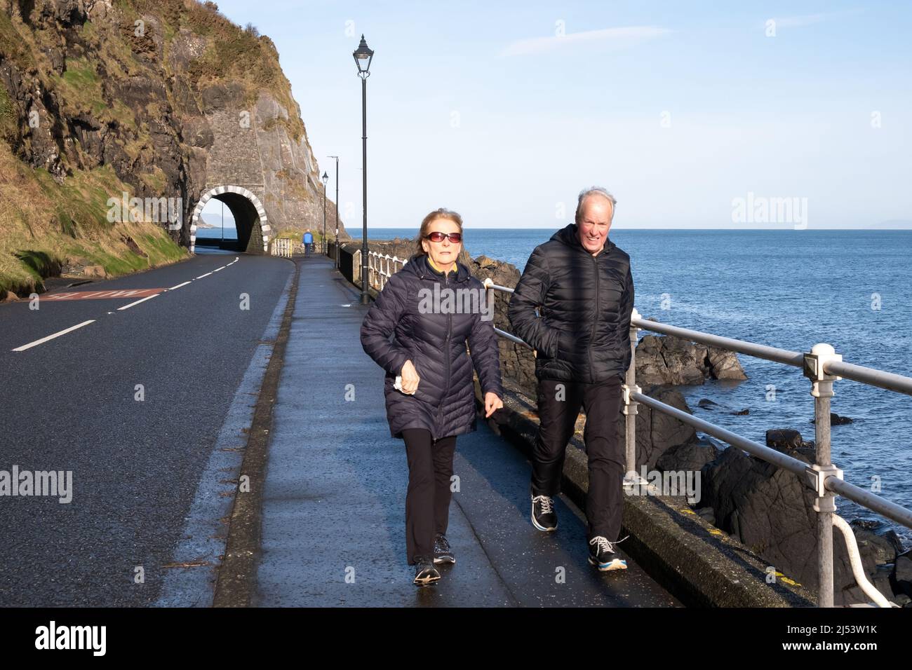 Couple walking alongside the ocean just outside Drains Bay on the Larne Coast in County Antrim Northern Ireland. Stock Photo