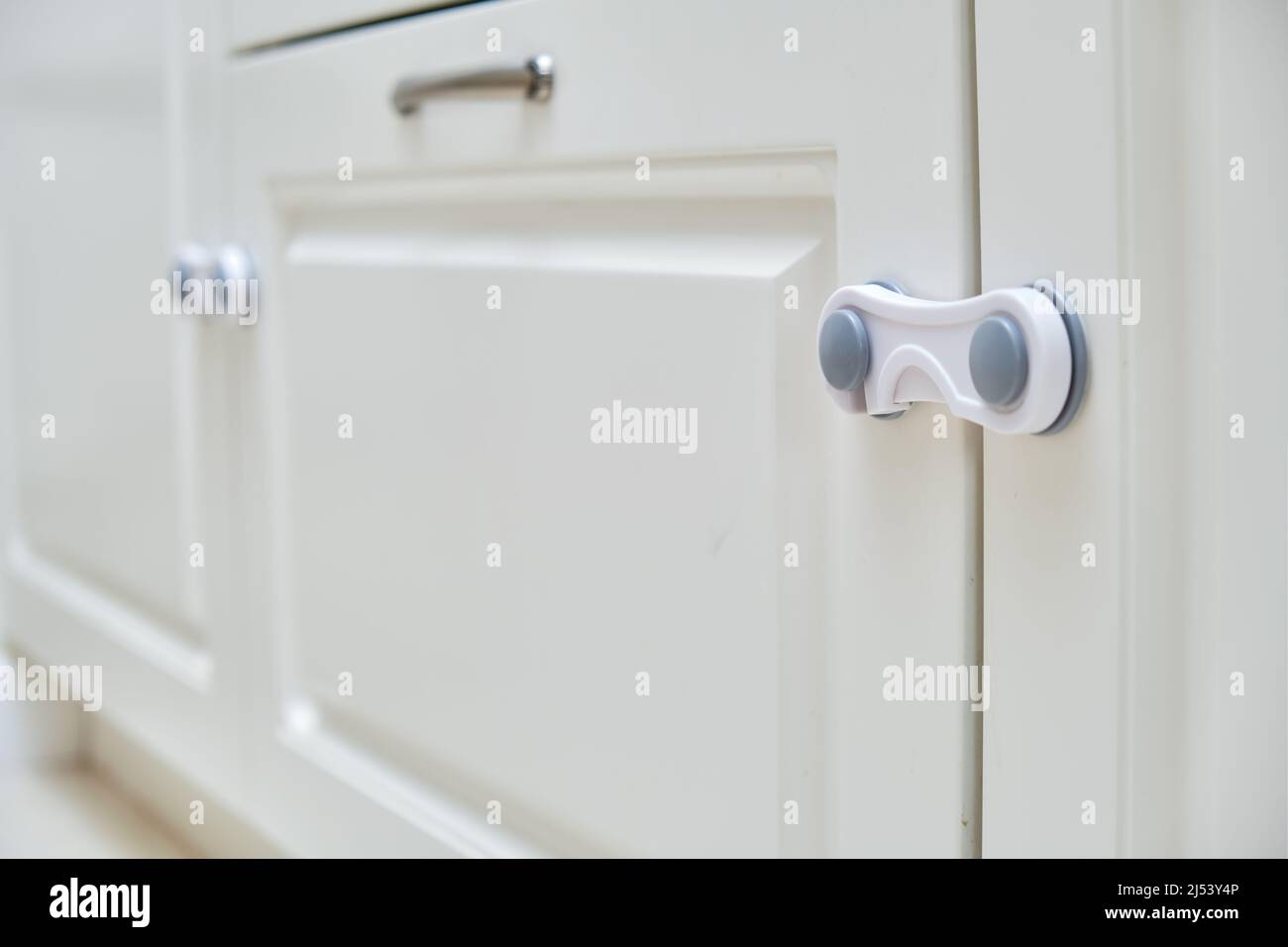 Doors of white kitchen blocked from children. Lock furniture
