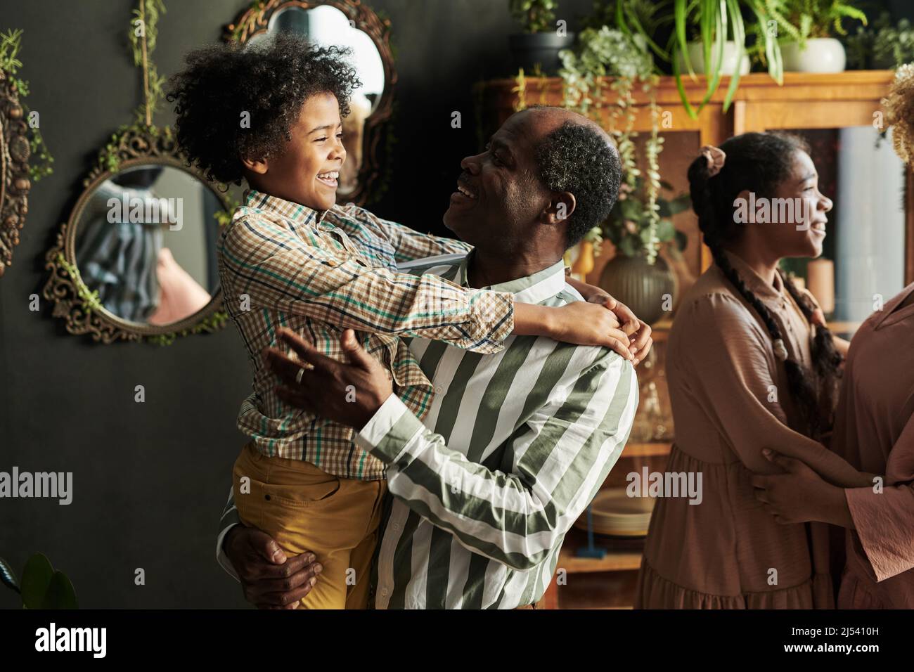 Happy African grandfather talking to his grandson during home party