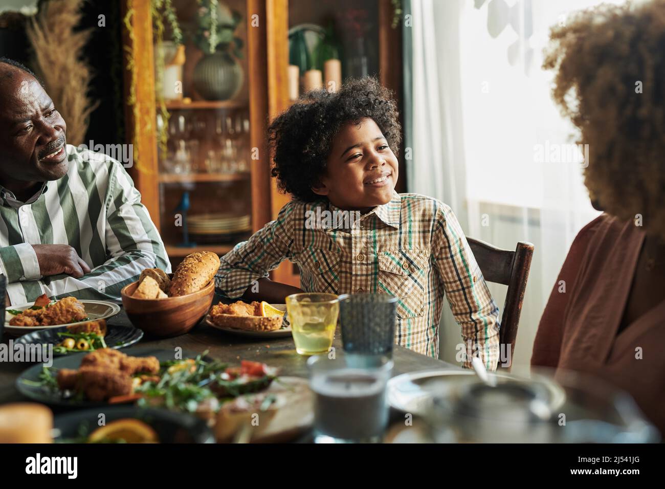 African little boy sitting at dining table and talking to his mother