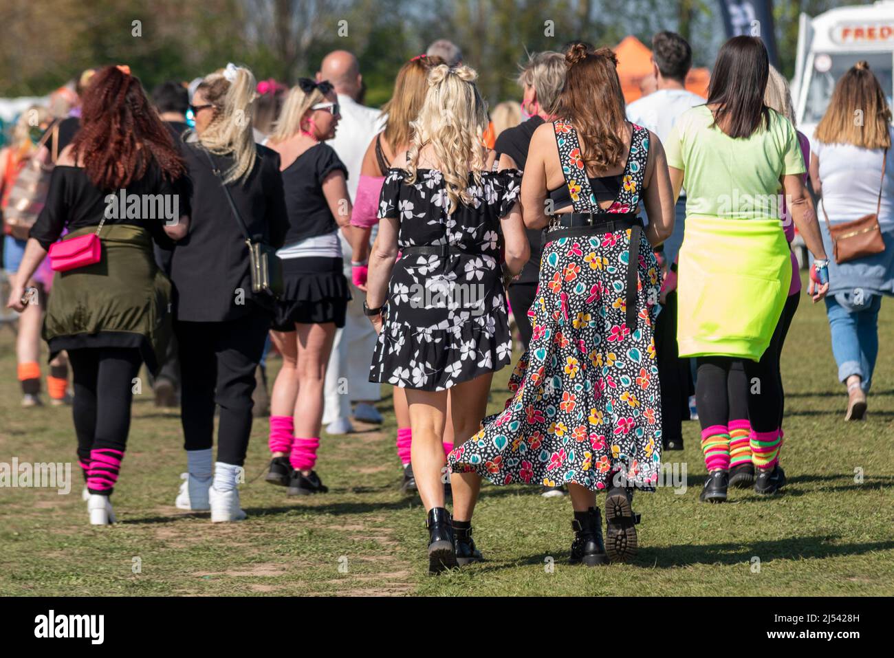 Pop fans arriving at a 1980s retro concert festival in Southend on Sea, Essex, UK. Female revellers in colourful clothing Stock Photo